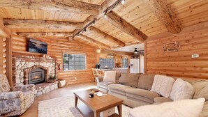 A cozy log cabin interior with a stone fireplace, wooden furniture, and a kitchen area. - THE Alps Lodge #2142 (Big Bear Lake)