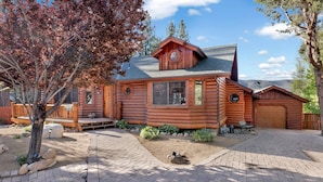 A log cabin with a covered porch, a garage, and a landscaped driveway. - THE Alps Lodge #2142 (Big Bear Lake)