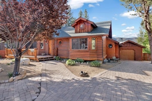 A log cabin with a covered porch, a garage, and a landscaped driveway.