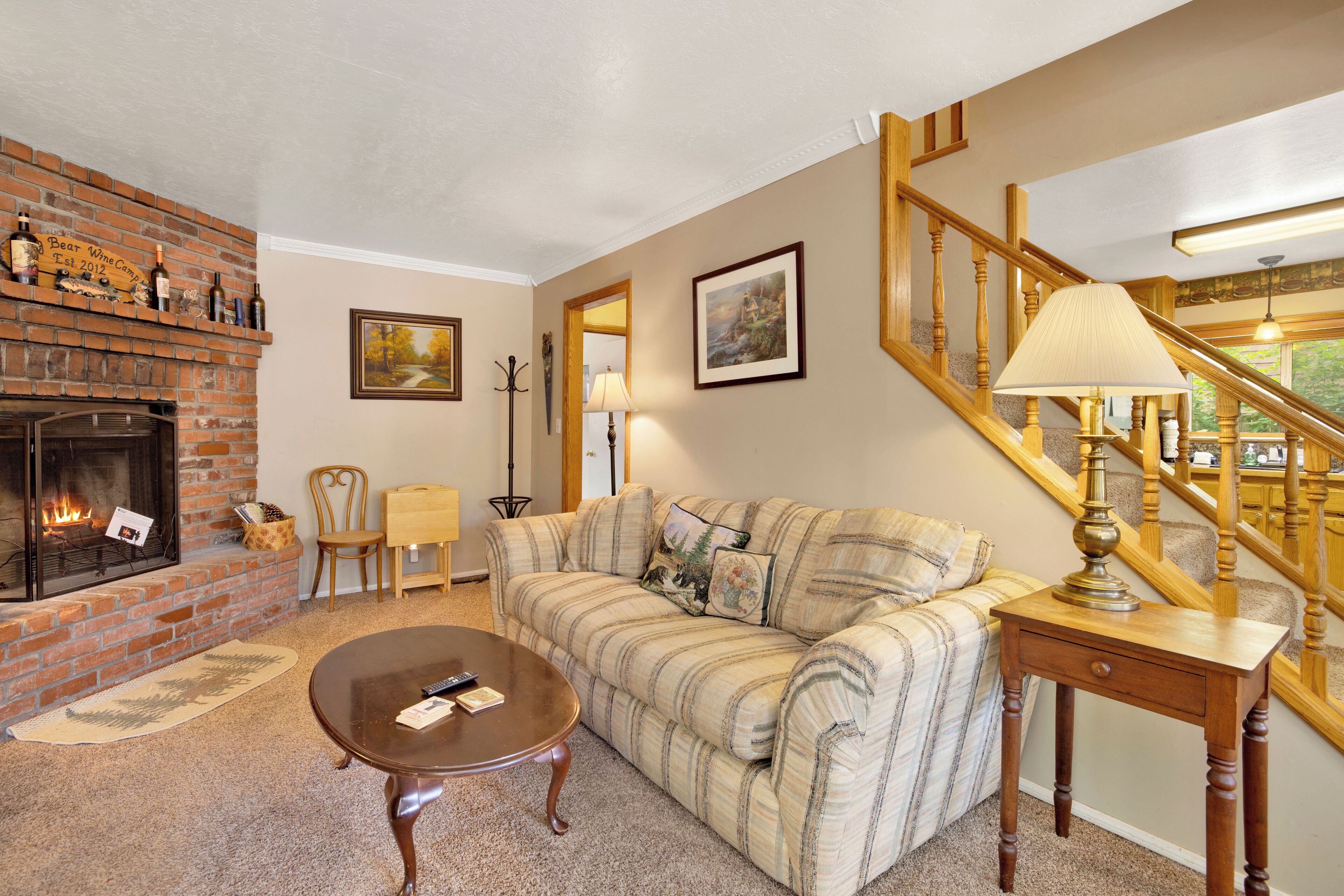 A living room with a brick fireplace, a wooden staircase, and a sofa.