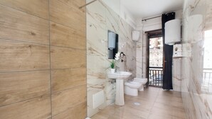 Un baño moderno con pared de madera, salpicadero de mármol, lavamanos, inodoro y bidé.