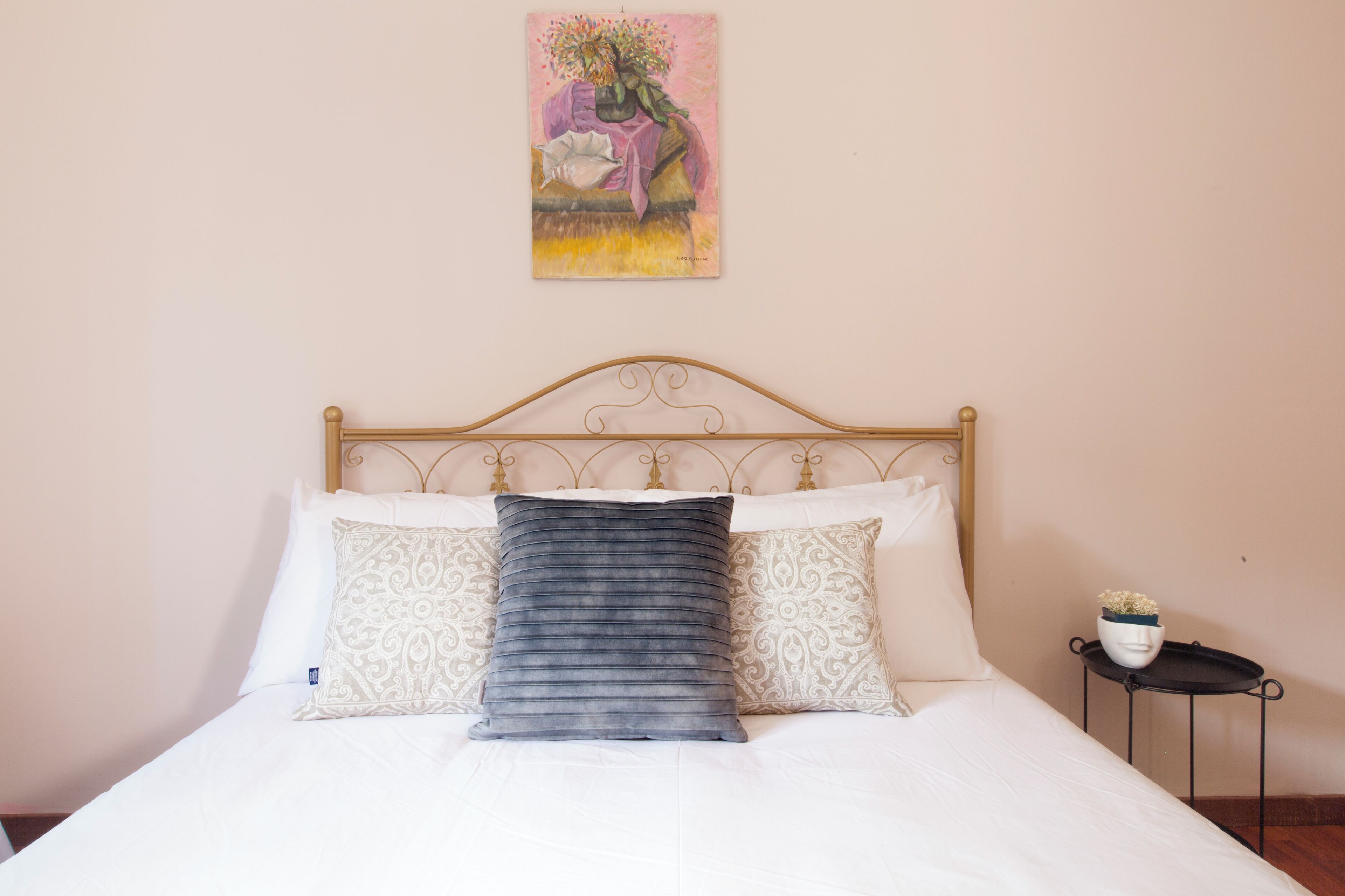 A neatly made bed with a headboard, two patterned pillows, and a single decorative pillow.