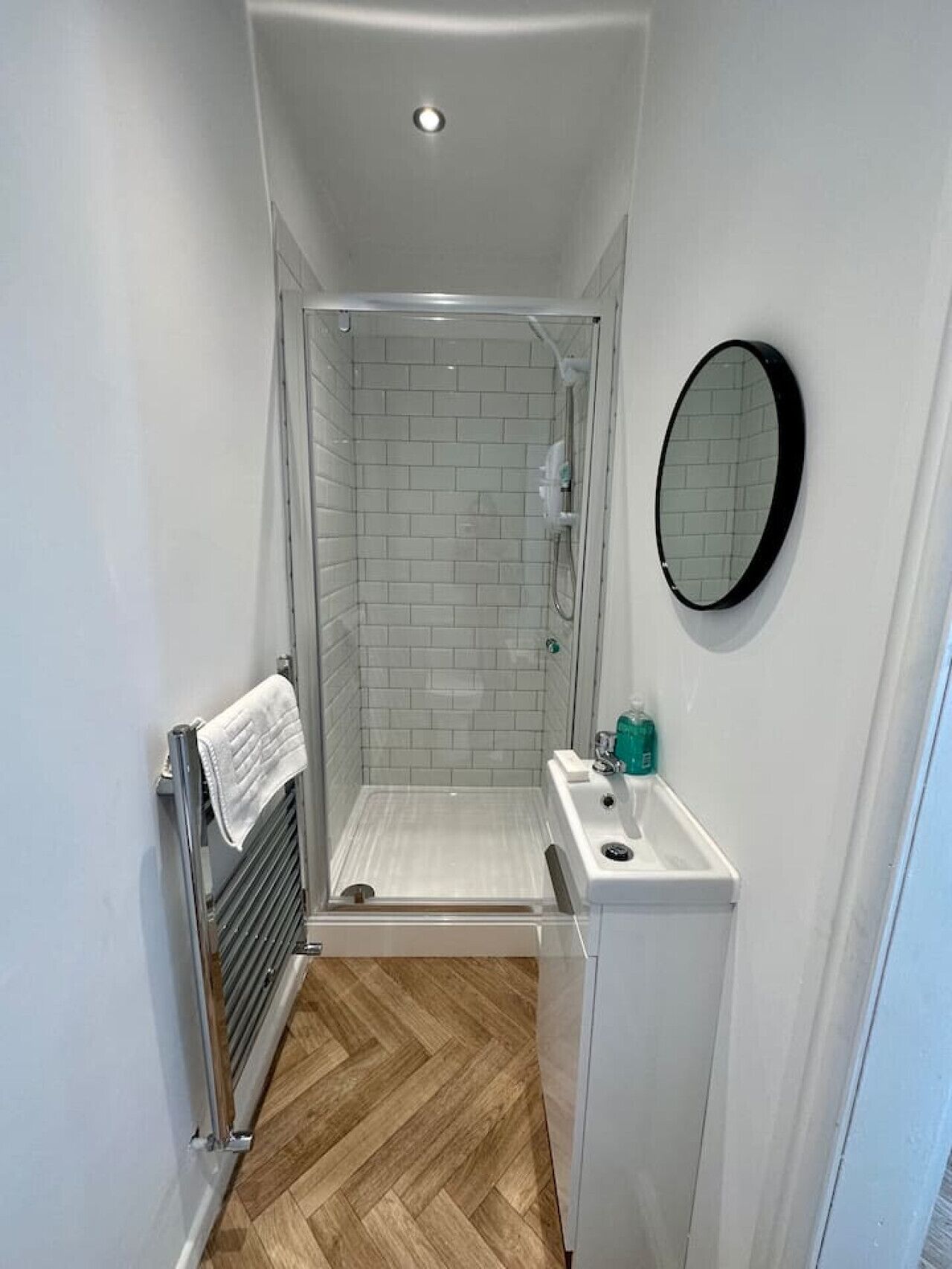 A small, modern bathroom with a shower, a sink, and a mirror.