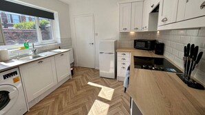 Eine moderne Küche mit weißen Schränken, einem eingebauten Backofen und einer Mikrowelle.
