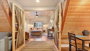 L’intérieur d’un chalet accueillant, avec un plancher en bois, un lit, un bureau et une table à manger.
