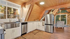 Une cuisine moderne avec des armoires blanches, des appareils en acier inoxydable et un plafond en bois.