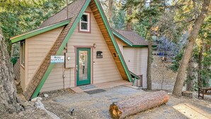 Une petite cabane avec un toit en pente, une porte verte et un symbole d’ours peint sur le mur.