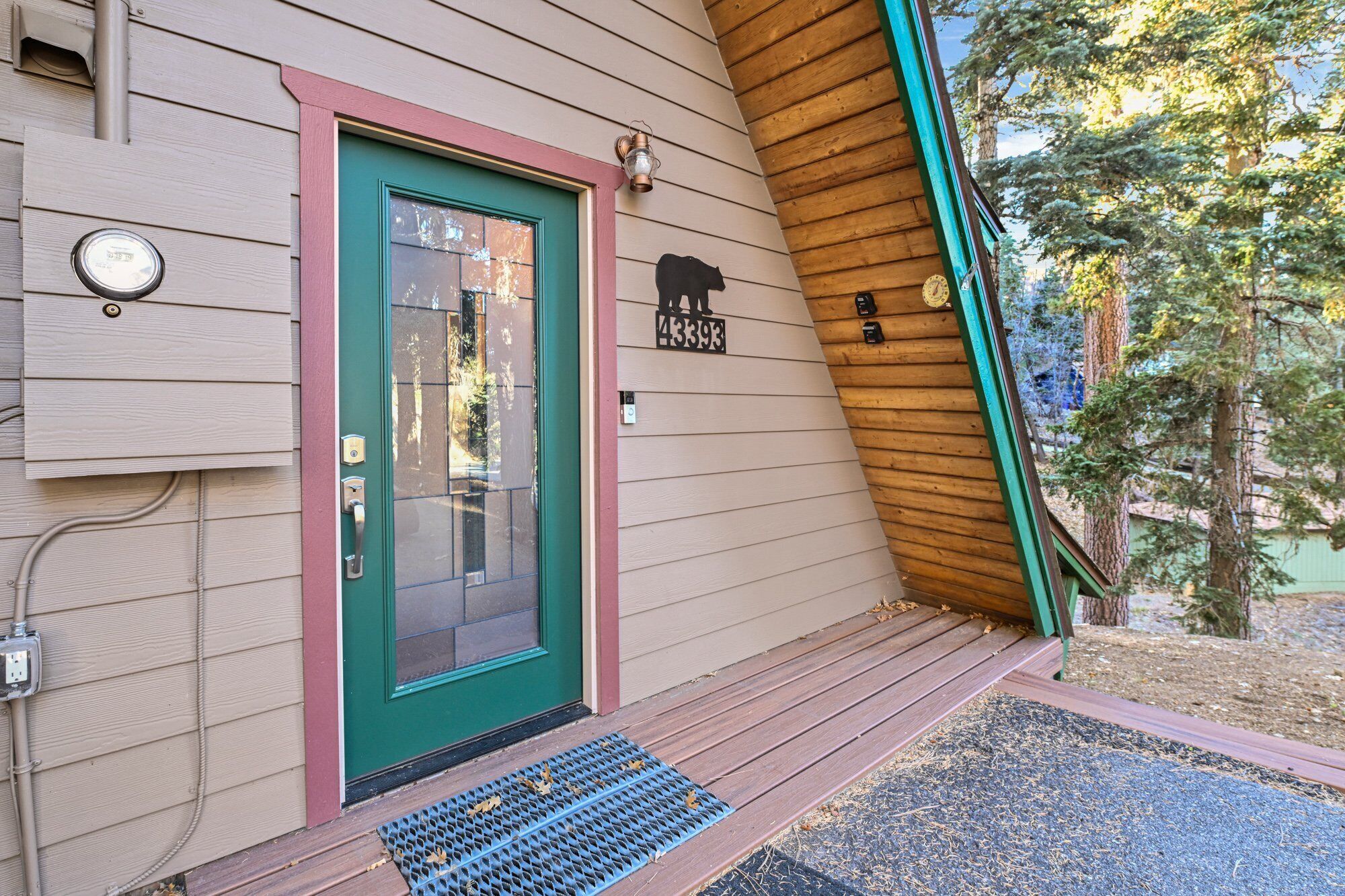Une maison avec une porte verte, une boîte aux lettres en forme d’ours et une façade en bois.