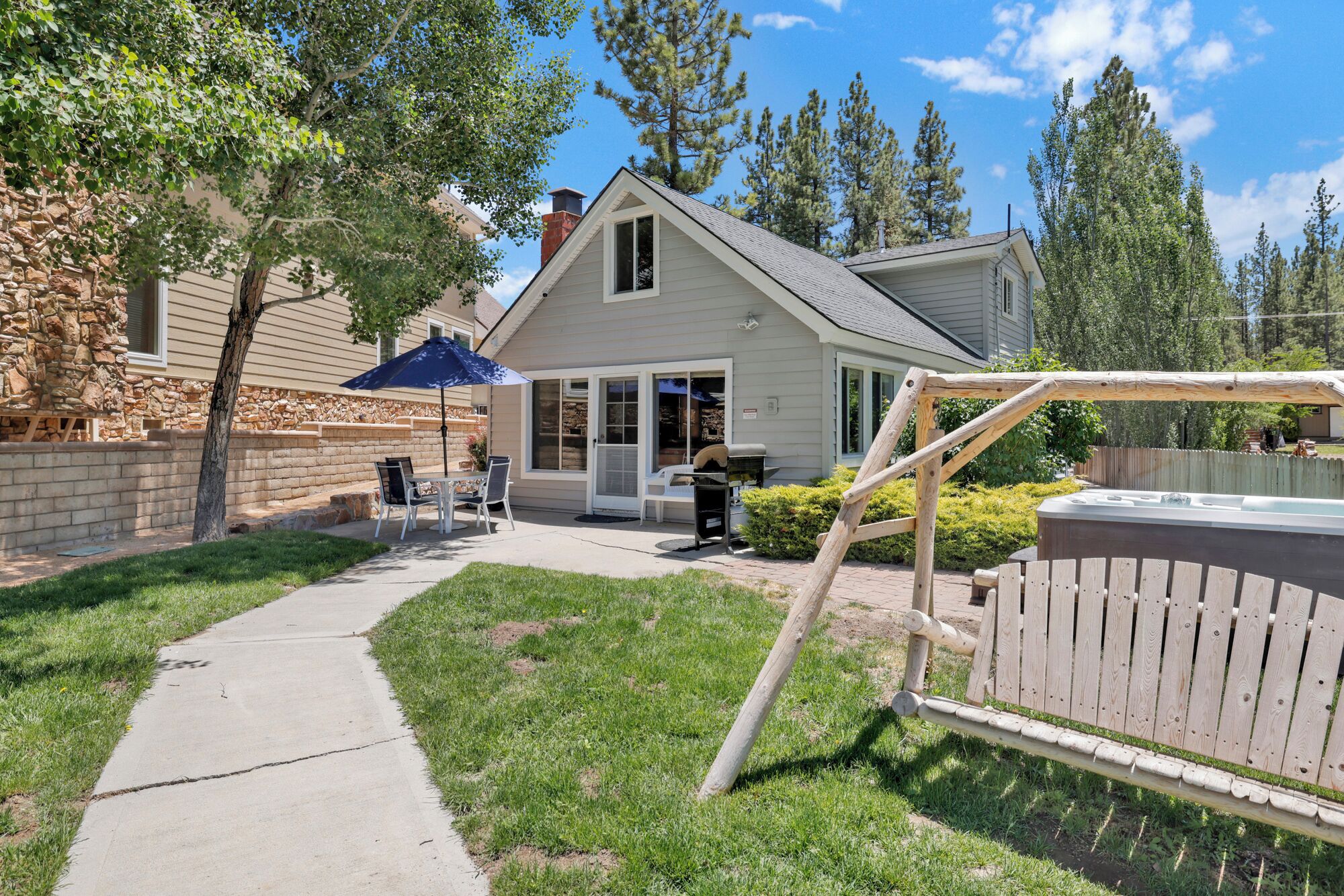 Une maison avec un patio, un jacuzzi et un mur en pierre.