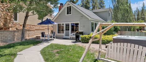 Une maison avec un patio, un jacuzzi et un mur en pierre.
