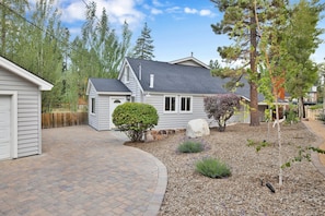 A single-story house with a grey roof, a front porch, and a small front yard with mulch and a few shrubs. - Lakeview Getaway #2120 (Big Bear Lake)