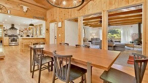 Un interior espacioso de madera con una gran mesa de comedor, cocina moderna y una zona de estar acogedora con chimenea.