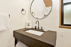Bathroom features a large mirror, single sink, and towel rack.