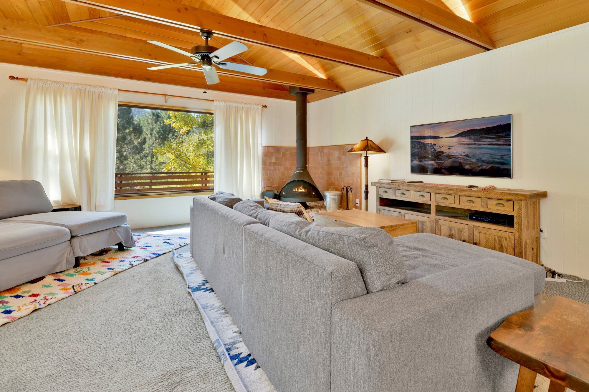 Ein gemütliches Wohnzimmer mit Sofa, Fernseher, Kamin und Deckenventilator.