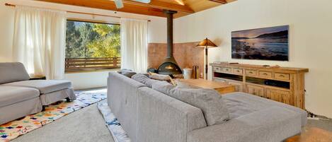 Ein gemütliches Wohnzimmer mit Sofa, Fernseher, Kamin und Deckenventilator.