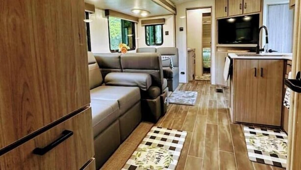 A compact RV interior with a seating area, kitchenette, and a small bathroom. - City-Accessible Camper (Goldston)