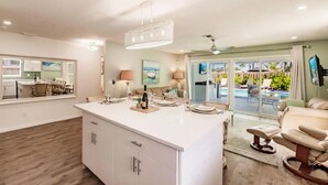 Amplia sala de estar con una isla grande, una mesa de comedor y vista al área de una piscina exterior.