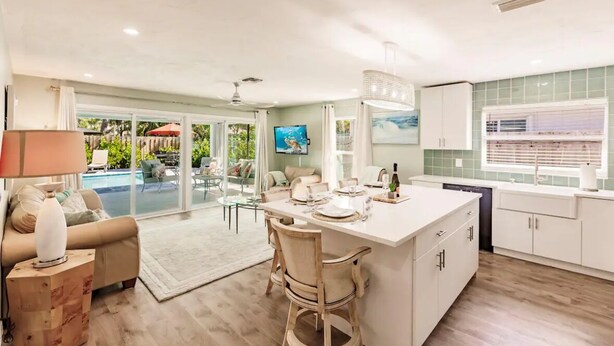 Amplia sala de estar con una isla grande, una mesa de comedor y una cocina con armarios blancos y un salpicadero de azulejos.