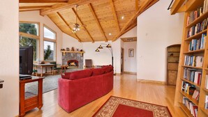 Un salon spacieux avec un canapé rouge, des étagères en bois, une cheminée et une grande fenêtre.