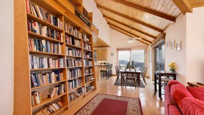 Une bibliothèque spacieuse avec des étagères en bois, un coin repas avec une table et des chaises, et un canapé rouge.