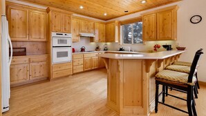 Une cuisine spacieuse avec des meubles en bois, un four double et un grand îlot central doté de tabourets de bar.
