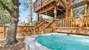 A hot tub area with a wooden deck and a view of a house in the background. - Luxury Lodge #1888 (Big Bear Lake)