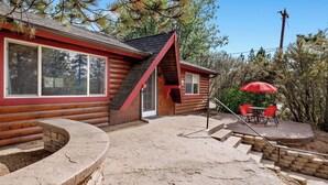 A log cabin with a red exterior, a brick staircase, and a patio area with outdoor furniture. - Moulin Rouge #2055 (Big Bear Lake)