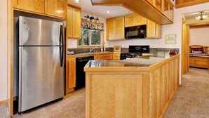A kitchen with wooden cabinets, stainless steel appliances, and a granite countertop. - Moulin Rouge #2055 (Big Bear Lake)