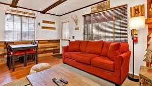 A cozy living room with a wooden dining table, red sofa, and a coffee table with remotes. - Mountain Getaway#2183 (Sugarloaf)