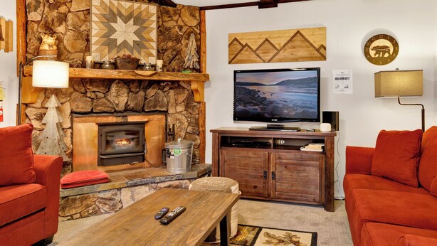 A cozy living room with a stone fireplace, a television, and red furniture. - Mountain Getaway#2183 (Sugarloaf)