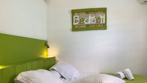 A bed with white linens and pillows, a green headboard, and a wall-mounted sign that reads "Bedroom". - VILLA ANAIS sea view, Trois Ilets, quiet, swimming pool, close to shops  (LES TROIS ILETS)