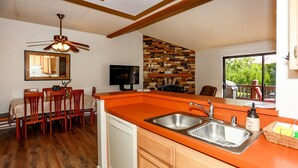 A compact kitchen with a wooden countertop, a sink, and a dining area with chairs. - Cienega Getaway #1952 (Big Bear Lake)