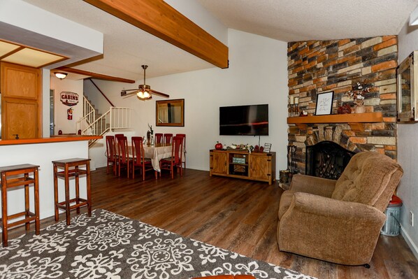 A living room with a fireplace, a TV, wooden furniture, and a staircase leading to another room.