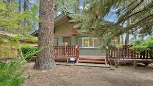 A cabin with a wooden deck, surrounded by trees and a dirt path. - LA Cerena Getaway #1960 (Big Bear Lake)
