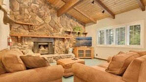 A cozy living room with a stone fireplace, comfortable sofas, and a television. - LA Cerena Getaway #1960 (Big Bear Lake)