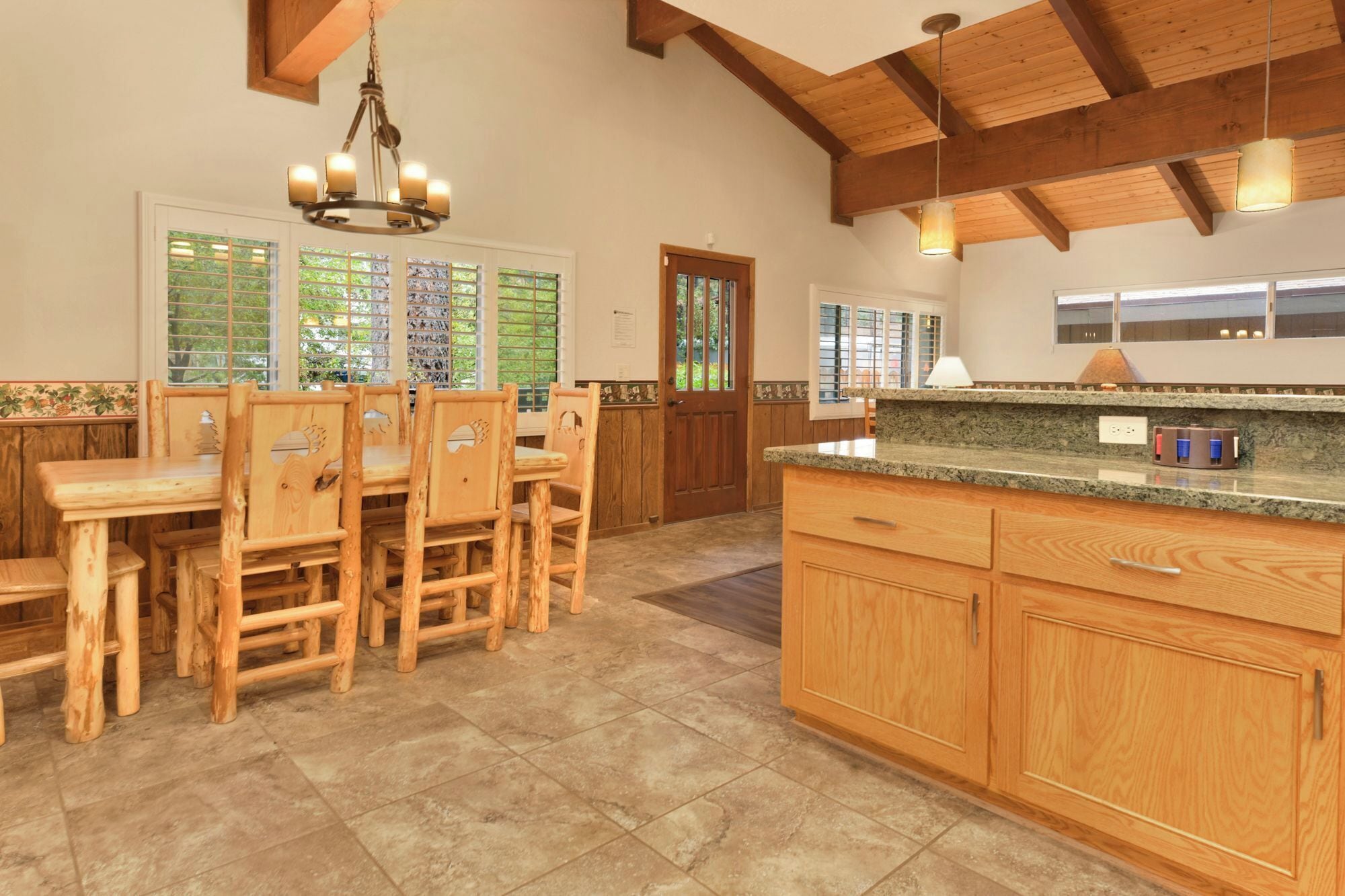 A spacious kitchen with wooden cabinets, a granite countertop, and a dining area with wooden chairs.