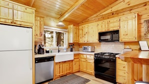 A wooden cabin kitchen with a refrigerator, dishwasher, microwave, stove, and toaster. - Crescenta Pines LOG Cabin #2346 (Big Bear City)