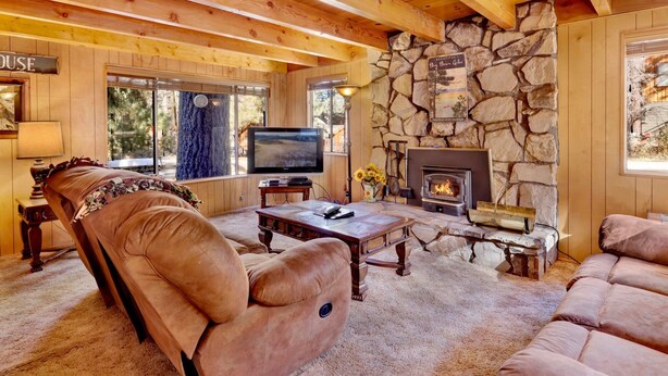 A cozy living room with a stone fireplace, comfortable seating, and a television. - Paradise IN Cedar #2095 (Big Bear Lake)
