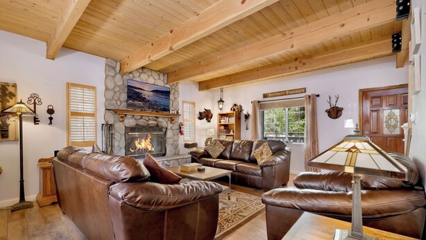 A cozy living room with leather sofas, a stone fireplace, and a television mounted above it. - Whiskey Mountain Lodge - 2028 (Sugarloaf)