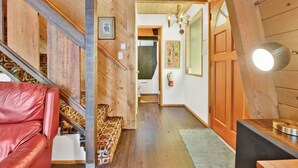 A wooden interior with a staircase, a red leather sofa, and a wooden table with a lamp. - Quail's Call #2415 (Big Bear Lake)