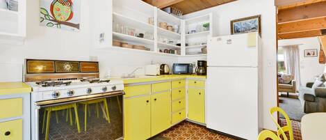 Una cocina con armarios amarillos, estufa y refrigerador.