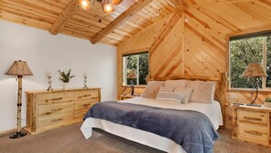 A wooden cabin bedroom with a bed, nightstands, and a ceiling fan. - Three Bears INN #2147 (Big Bear City)