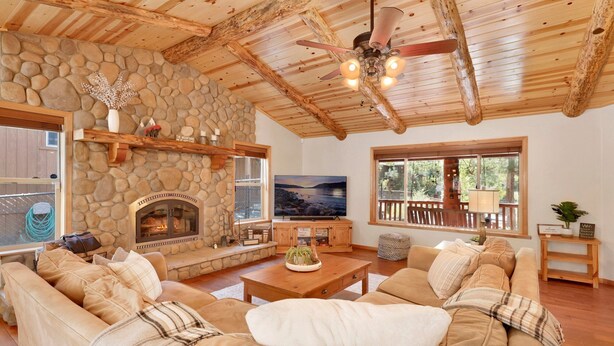 A cozy living room with a stone fireplace, a large TV, and a comfortable seating area. - Three Bears INN #2147 (Big Bear City)