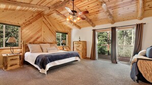 A cozy bedroom with a wooden ceiling, a bed with pillows, a nightstand, a dresser, and a balcony with curtains. - Three Bears INN #2147 (Big Bear City)