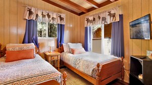 A wooden-paneled room with two beds, each with patterned bedding and curtains featuring animal silhouettes. - SKI View Chalet #2215 (Big Bear Lake)