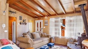 A cozy room with a wooden ceiling, a sofa, a stone fireplace, and a rustic decor. - SKI View Chalet #2215 (Big Bear Lake)