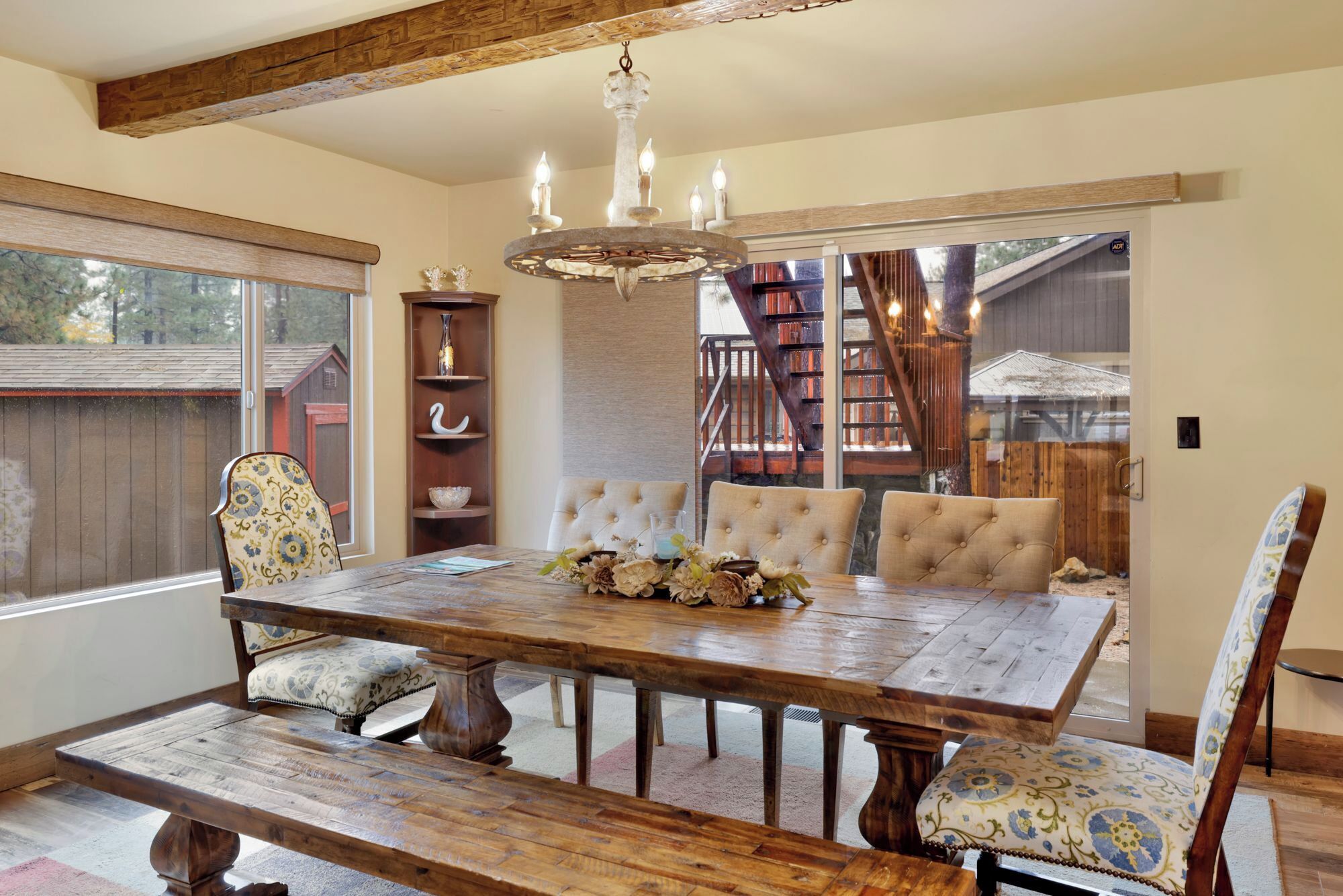 A dining room with a wooden table, cushioned chairs, and a chandelier.