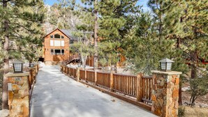 A wooden cabin with a stone entrance, surrounded by pine trees. - Gold Rush Lodge #2352 (Big Bear Lake)