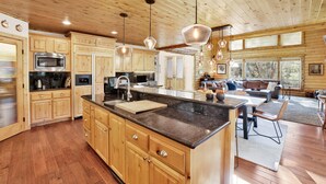 A spacious kitchen with wooden cabinets, a large island, and pendant lighting. - Gold Rush Lodge #2352 (Big Bear Lake)