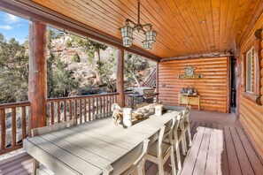 Um deck de madeira com mesa e cadeiras, uma escada de madeira e vista para as montanhas.